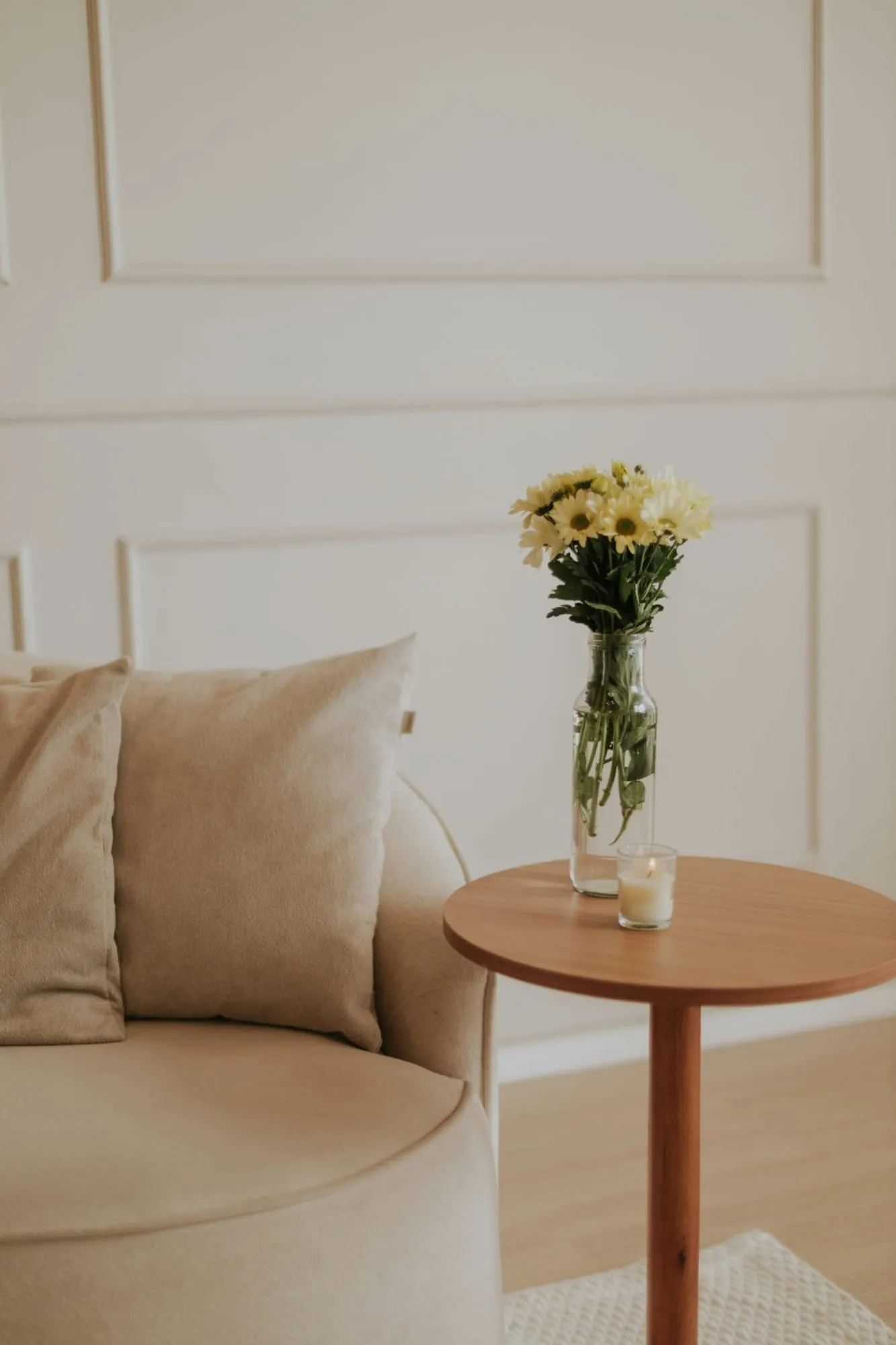 A light-coloured armchair next to a side table with flowers